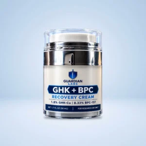 Close-up of a glass cosmetic bottle with a blue shield logo and label reading "Guardian Labs" and "GHK+BPC Recovery Cream".