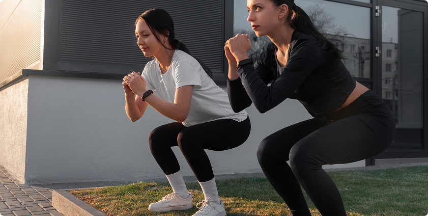 Two athletes doing squats outdoors